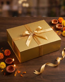 Chai Gold Diwali gift box closed: gold magnetic box tied with a gold satin ribbon, with diyas and marigolds — photo 2